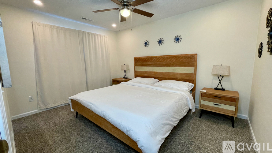 A bedroom with a bed, nightstand, and ceiling fan.