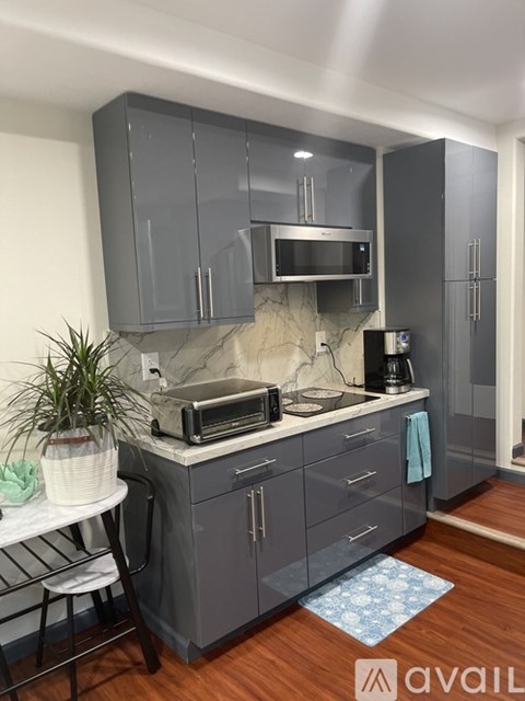 A kitchen with grey cabinets and a marble backsplash.