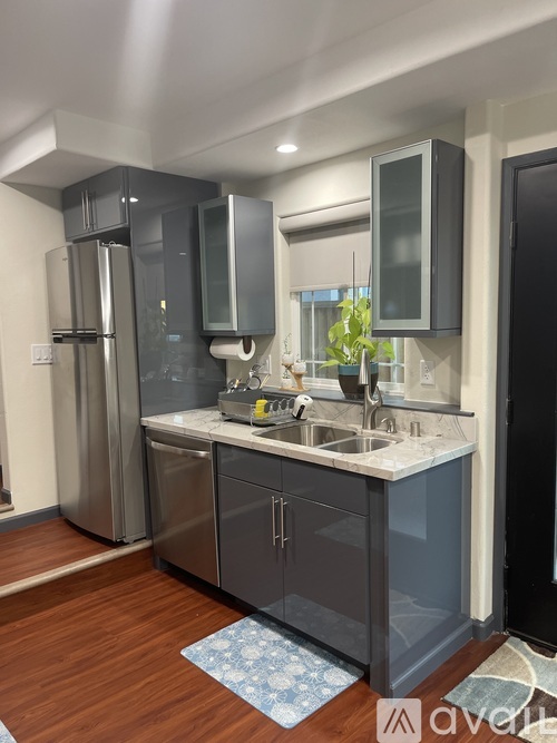 A kitchen with a sink, refrigerator, and cabinets.