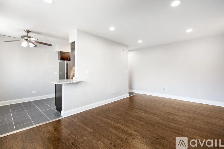A spacious room with wooden flooring and a ceiling fan.