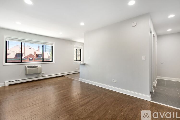 A spacious room with wooden flooring and a window showing an outdoor view.