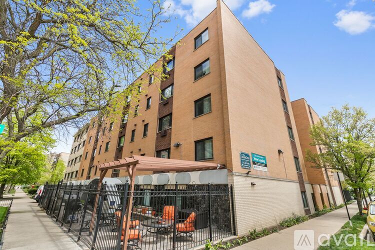A tall brick building with a black fence in front.