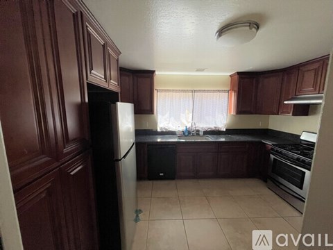 A kitchen with brown cabinets and a black refrigerator.