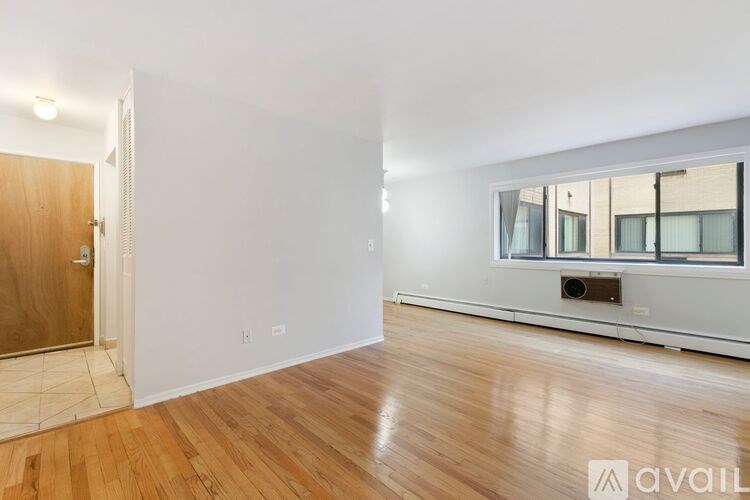 A room with wooden floors and a window with a view of a building outside.