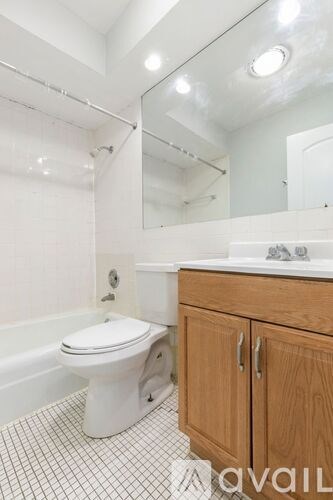 A white toilet sits in a bathroom with a wooden cabinet.