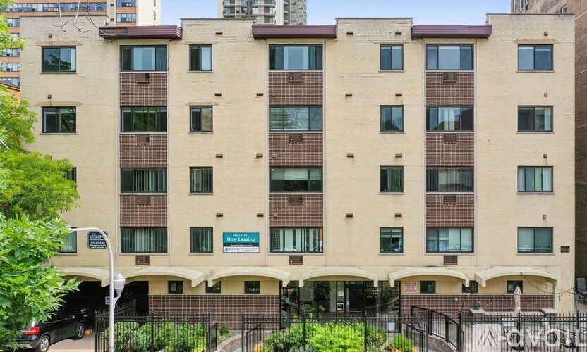 A large beige apartment building with a black fence in front.