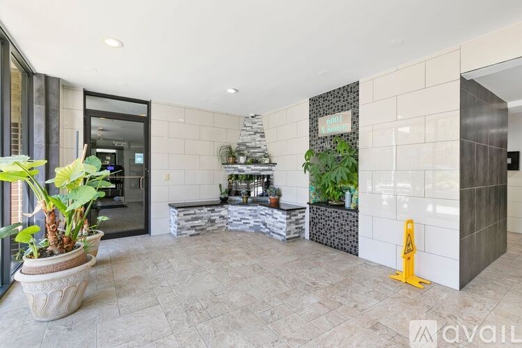 A large potted plant sits in the middle of a tiled floor in a modern room.