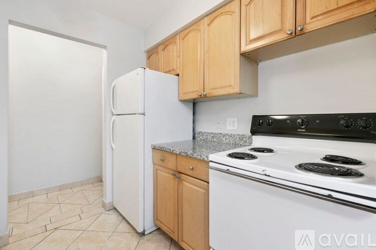 A kitchen with a white refrigerator, wooden cabinets, and a black stove top.