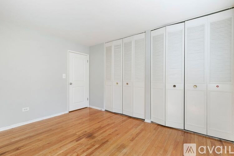 A room with white cupboards and wooden flooring.