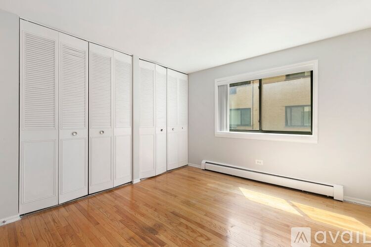 A room with a window, a radiator, and a row of white cupboards.