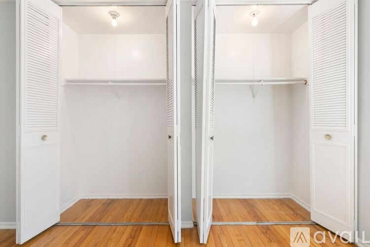 A white closet with a wooden floor and a hanging rail.
