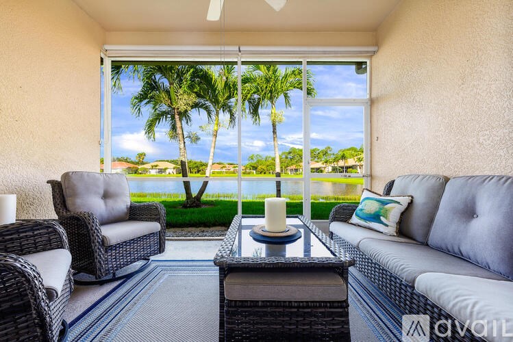 A living room with a view of palm trees through the window.