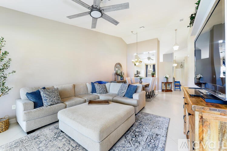 A living room with a white couch and a grey rug.