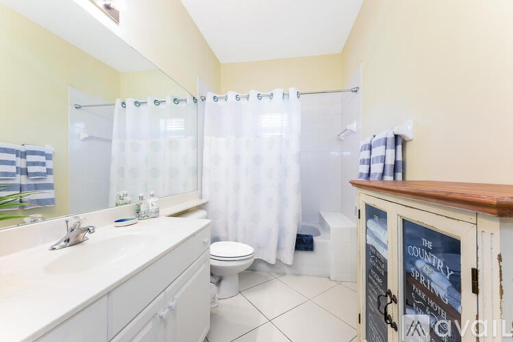 A bathroom with a white sink, toilet, and shower curtain.