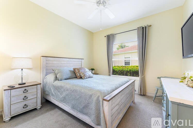 A bedroom with a large bed, a dresser, and a television.