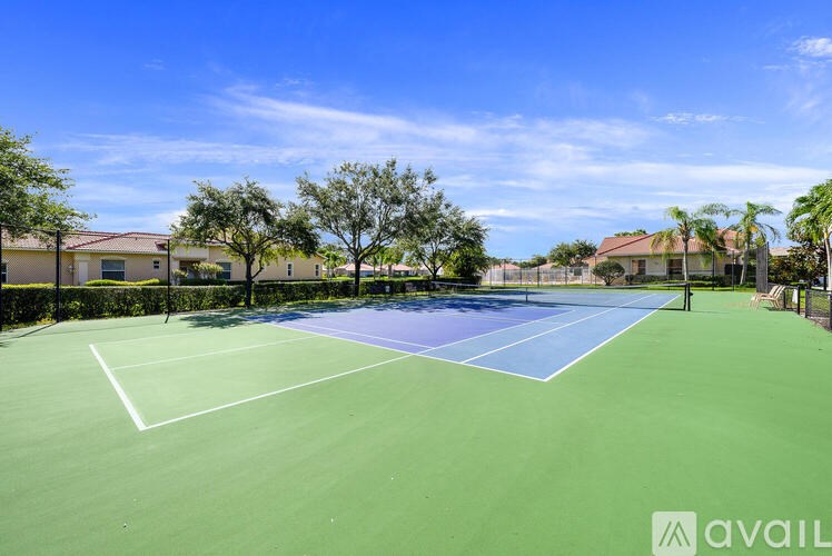 A tennis court with a blue and green surface surrounded by a fence and trees.