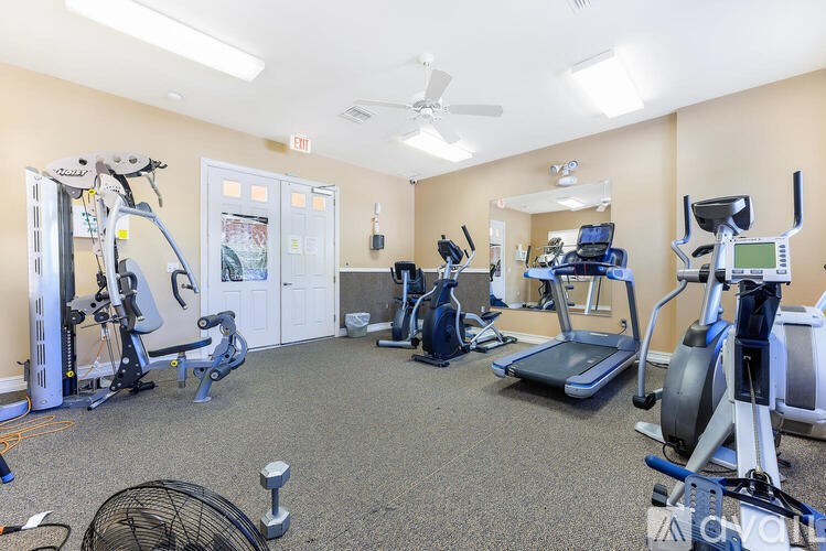 A gym with a variety of exercise equipment including treadmills, elliptical machines, and a stationary bike.