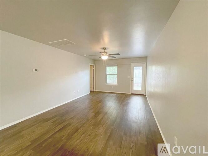 A spacious room with wooden flooring and a ceiling fan.
