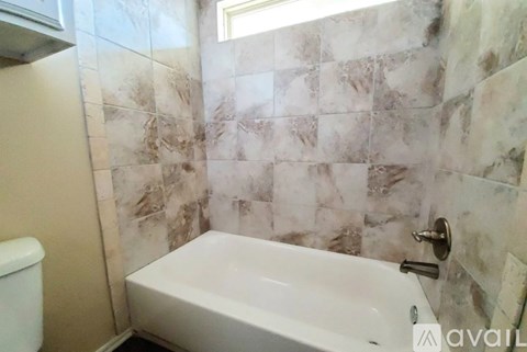 A bathroom with a white tub and tiled walls.