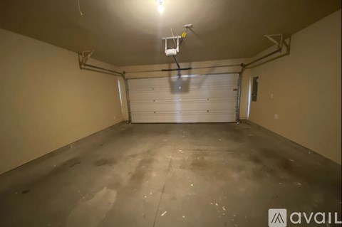 A spacious garage with a closed white door and a light hanging from the ceiling.