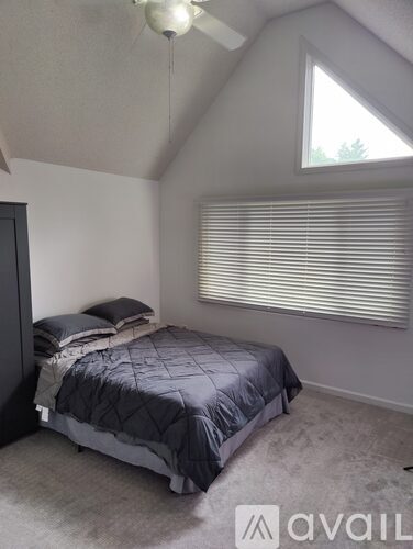 A bedroom with a bed and a ceiling fan.