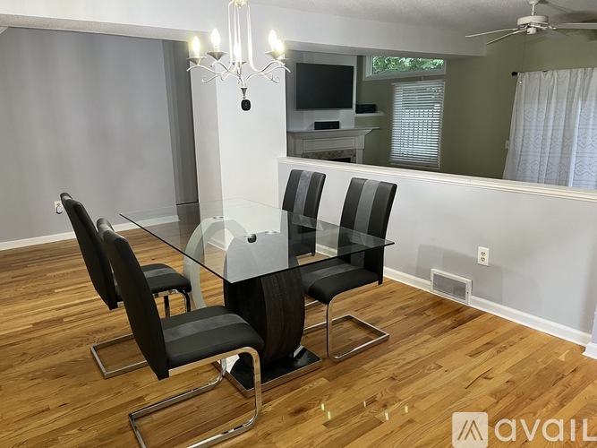 A modern dining room with a glass table and black chairs.