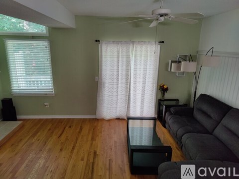 A living room with a black couch and a glass coffee table.
