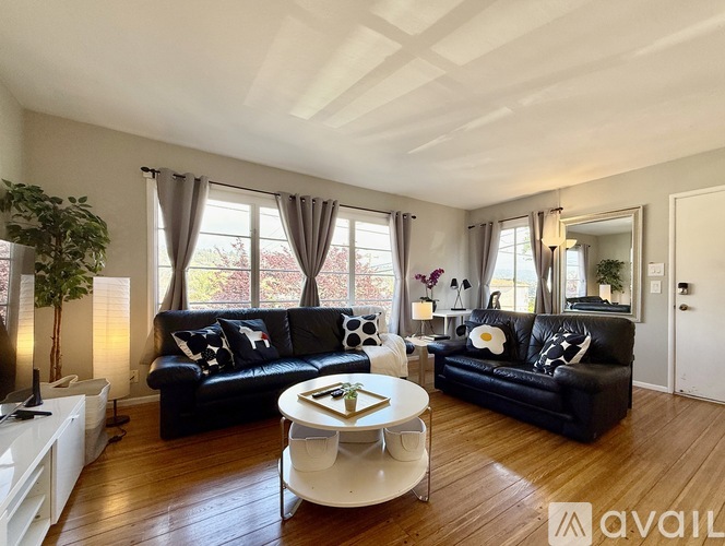 A living room with black leather sofas and a white coffee table.