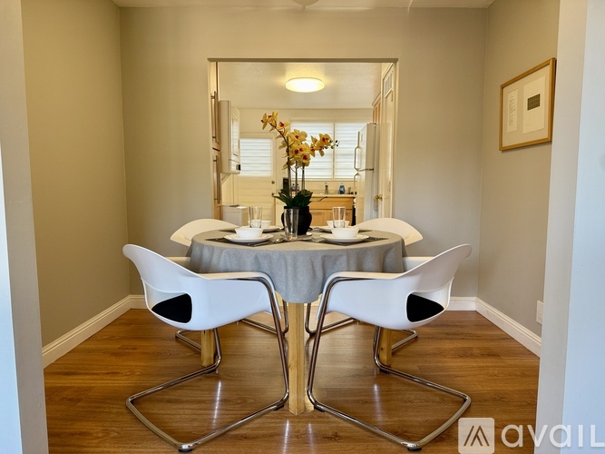 A dining room with a round table and white chairs.