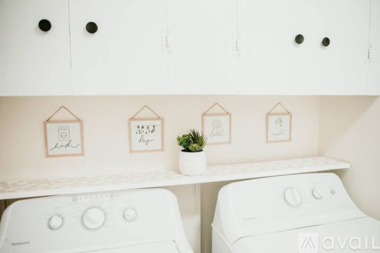 A laundry room with two washing machines and three pictures on the wall.