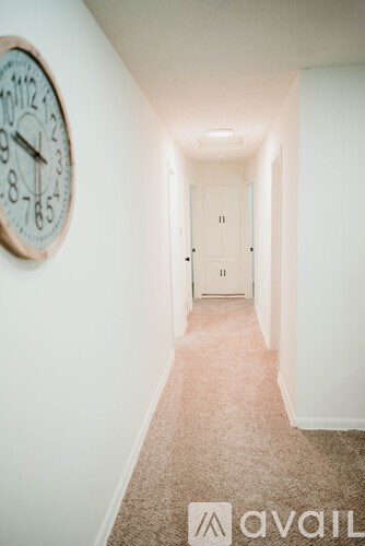 A hallway with a clock on the wall and a door at the end.