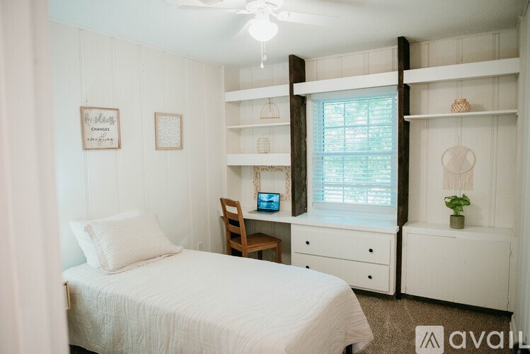 A bedroom with a bed, desk, and shelves.