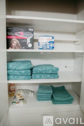 A white shelf with towels and a magazine.