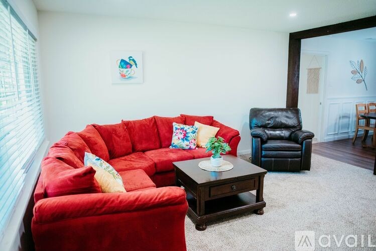 A red sofa with a cushion and a small table in front of it.