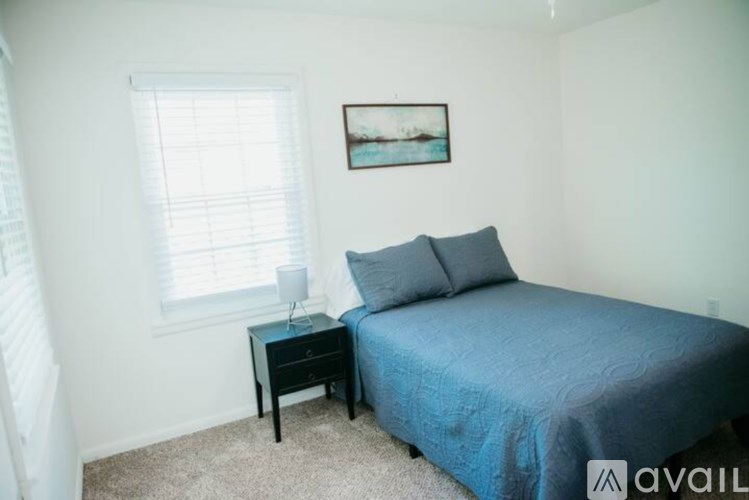 A bedroom with a bed, nightstand, and window.