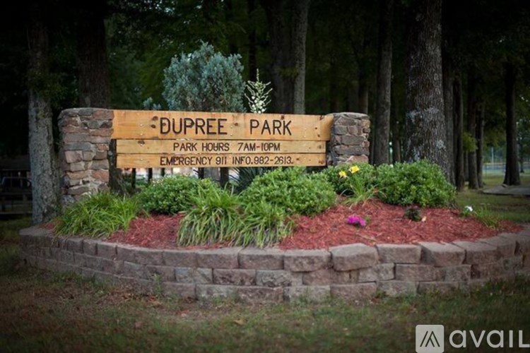 A wooden sign for Dupree Park is surrounded by plants and rocks.