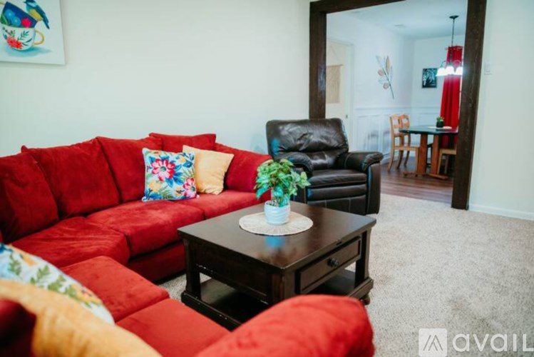 A living room with a red couch and a black leather chair.