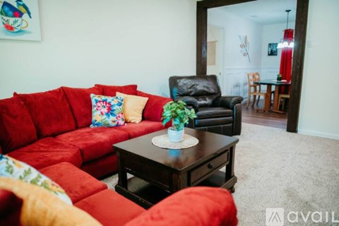 A living room with a red couch and a black leather chair.