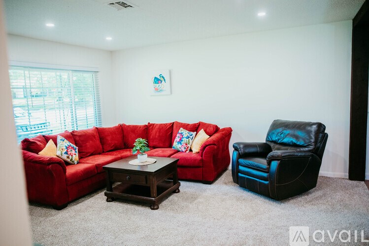 A living room with a red couch, a black leather chair, and a small table with a plant on it.