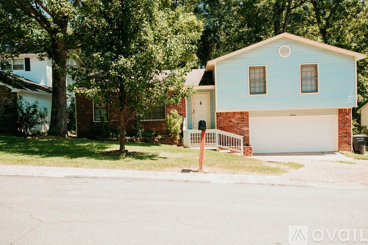 A blue house with a white garage door is surrounded by trees.
