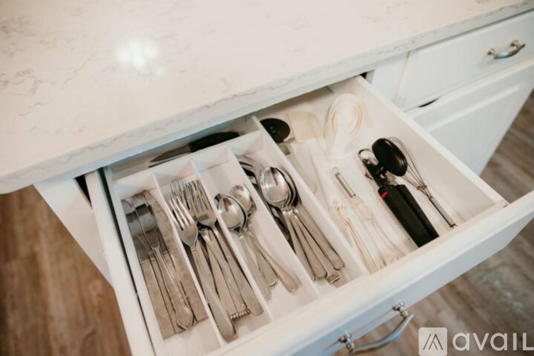 Drawer with silverware and a bottle of wine.