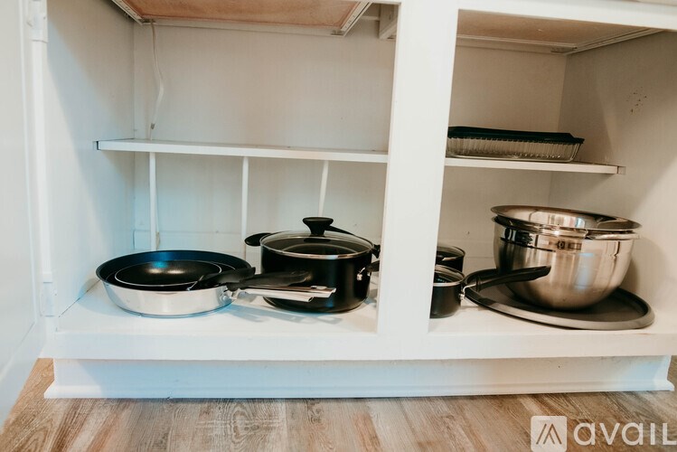 A white shelf with pots and pans on it.