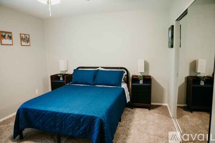 A bedroom with a blue bedspread and two nightstands.