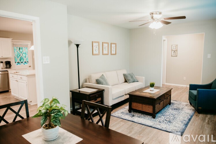 A living room with a white couch, a coffee table, and a ceiling fan.