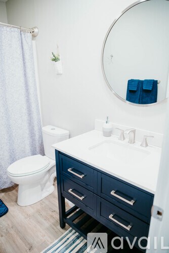 A bathroom with a white toilet and a white sink with a blue towel on the counter.