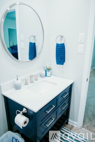 A bathroom with a white sink and blue towels.