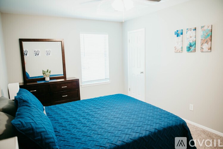 A bedroom with a blue bedspread and a mirror on the dresser.