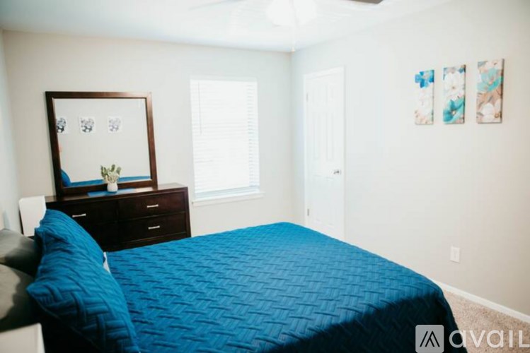 A bedroom with a blue bedspread and a framed picture on the wall.