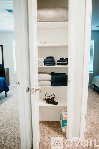 A white closet with towels and shoes on shelves.
