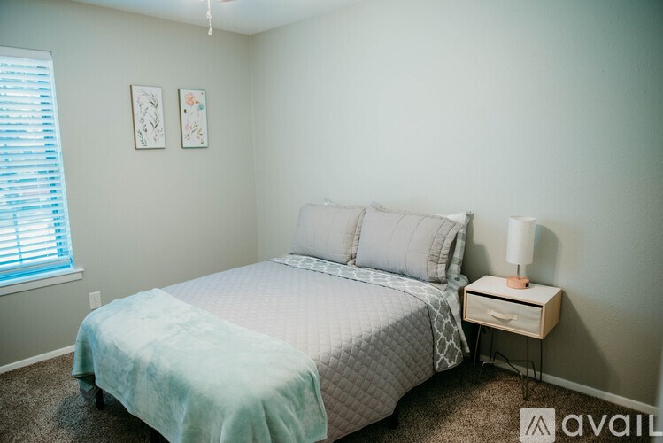 A bedroom with a bed, nightstand, and two pictures on the wall.